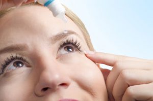Photo of woman putting eye drops in her eye